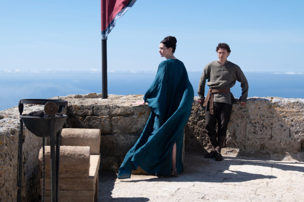 L to R Anne Hathaway is Penelope and Tom Holland is Telemachus in THE ODYSSEY standing on the roof of their castle in...