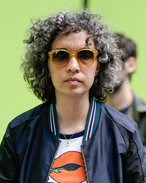 Woman wearing a curly gray shag sunglasses graphic tshirt and jacket