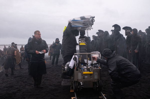 Director Christopher Nolan  on set of his film THE ODYSSEY standing on a black sand beach in Iceland.