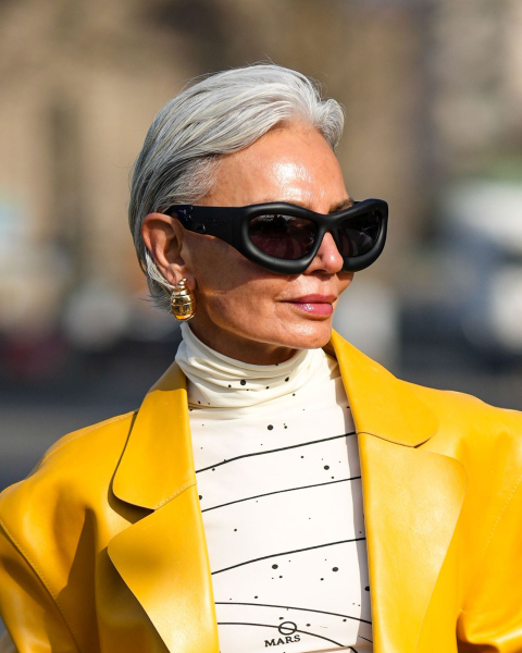 Woman wearing oversized sunglasses offwhite and black turtleneck and yellow leather jacket